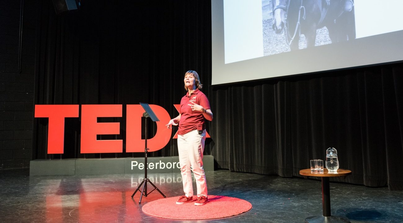 Emma Sheardown giving talk in front of sign saying TEDX Peterborough